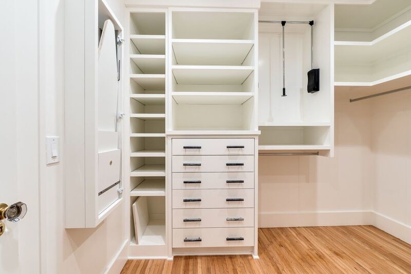 Diseño de armario vestidor unisex tradicional renovado de tamaño medio con puertas de armario blancas, suelo de madera clara y suelo beige