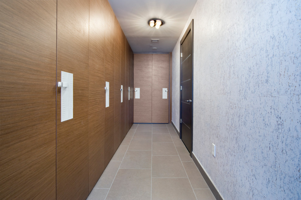 Aménagement d'une grande armoire encastrée moderne en bois brun neutre avec un placard à porte plane, un sol en carrelage de porcelaine et un sol gris.