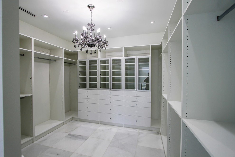 Idée de décoration pour un grand dressing room minimaliste neutre avec un placard à porte plane, des portes de placard blanches, un sol en marbre et un sol blanc.