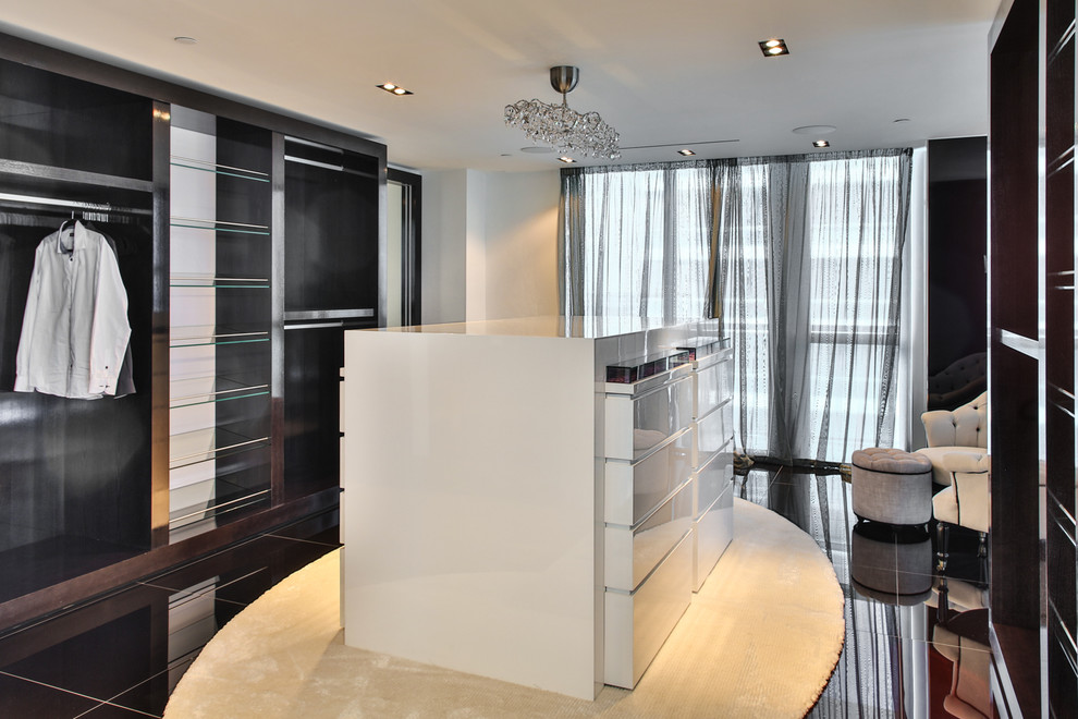 This is an example of a large contemporary wardrobe in Miami with flat-panel cabinets, dark wood cabinets and marble flooring.