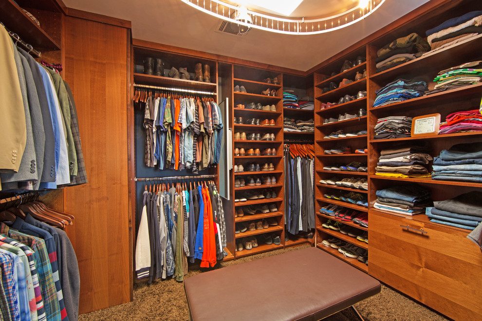 Idée de décoration pour un grand dressing room vintage en bois brun neutre avec un placard à porte plane et moquette.