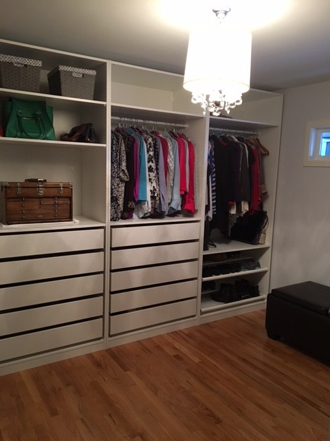 Photo of a medium sized modern walk-in wardrobe in Portland with flat-panel cabinets, white cabinets and medium hardwood flooring.