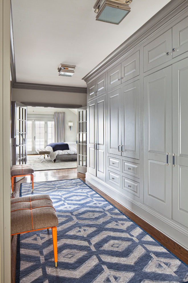 Modelo de armario y vestidor clásico renovado grande con armarios con paneles empotrados, puertas de armario grises y suelo de madera oscura