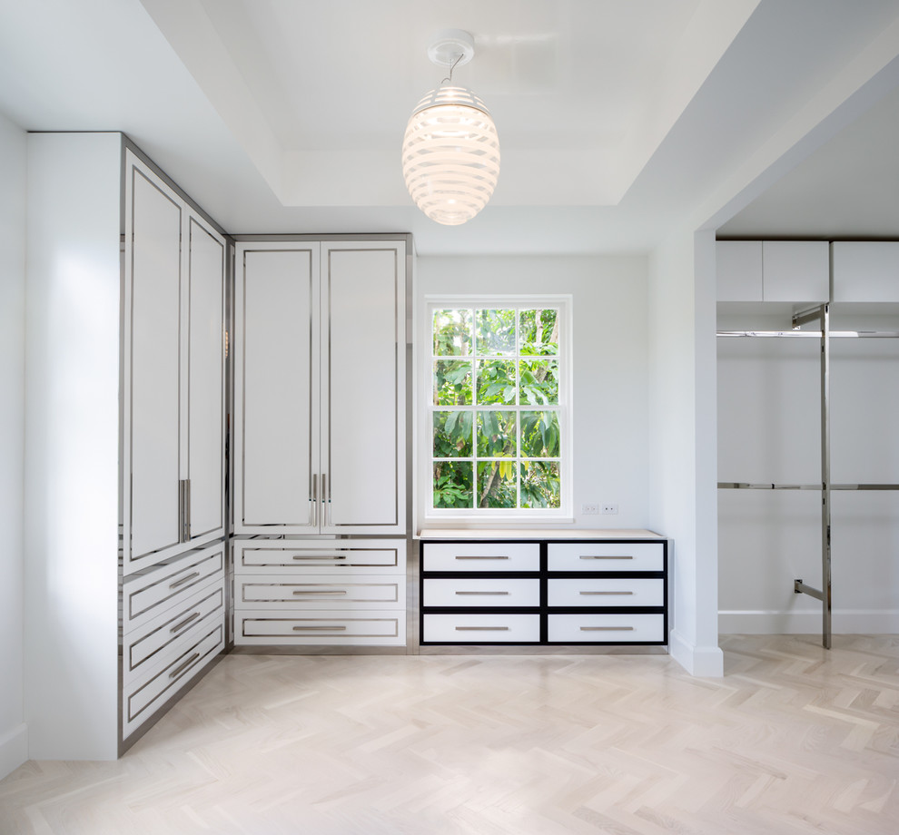 Photo of a large traditional gender neutral standard wardrobe in Miami with flat-panel cabinets, white cabinets and travertine flooring.