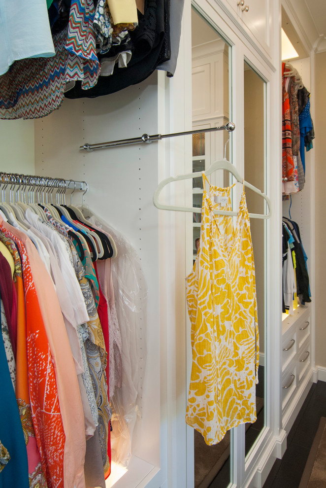 Imagen de vestidor unisex clásico de tamaño medio con armarios con paneles empotrados, puertas de armario blancas y suelo de madera oscura