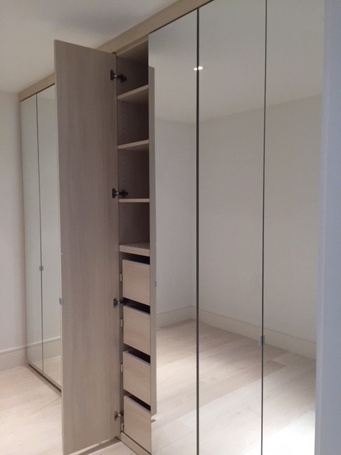 Foto de armario unisex contemporáneo grande con armarios tipo vitrina, suelo de madera clara y suelo beige