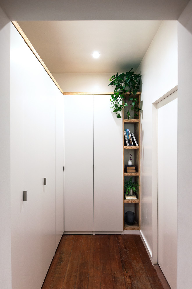 Exemple d'un petit dressing room tendance neutre avec un placard à porte plane, des portes de placard blanches, parquet foncé et un sol multicolore.