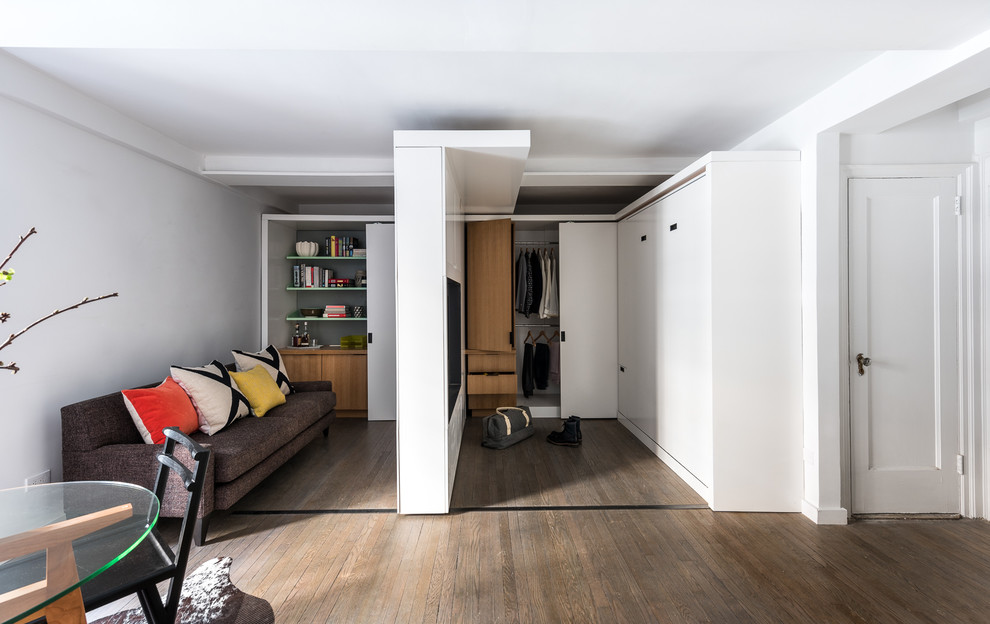Imagen de vestidor unisex moderno pequeño con armarios con paneles lisos, puertas de armario de madera clara y suelo de madera en tonos medios