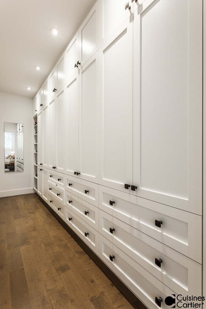 Idée de décoration pour un grand dressing room tradition neutre avec un placard à porte shaker, des portes de placard blanches et parquet foncé.
