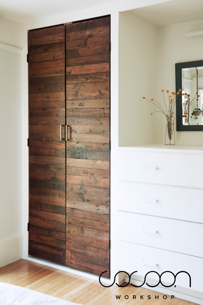 This is an example of a medium sized scandi gender neutral dressing room in San Francisco with flat-panel cabinets, dark wood cabinets and light hardwood flooring.