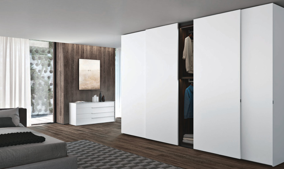 Cette photo montre un grand placard dressing moderne avec un placard à porte plane, des portes de placard blanches et un sol en bois brun.