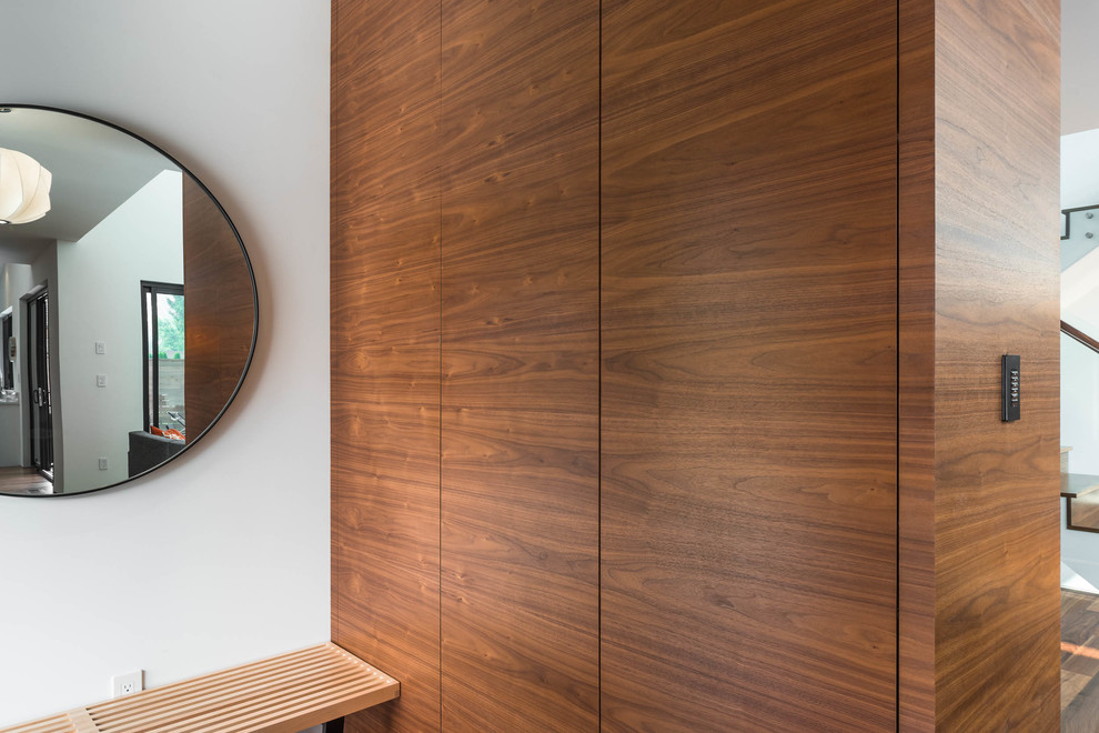 Immagine di un piccolo armadio o armadio a muro unisex minimalista con ante lisce, ante in legno scuro, pavimento in legno massello medio e pavimento marrone