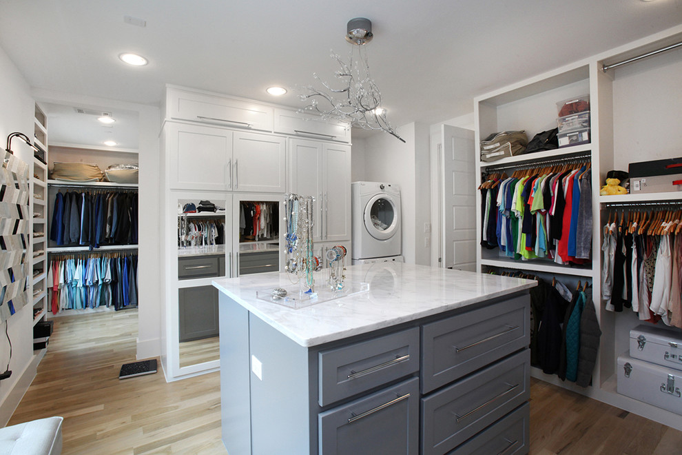 Imagen de armario vestidor unisex moderno grande con armarios estilo shaker, puertas de armario blancas y suelo de madera clara