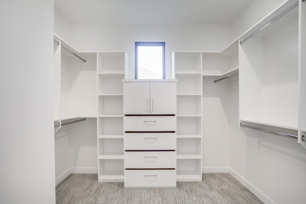 Photo of a large contemporary gender neutral walk-in wardrobe in Grand Rapids with flat-panel cabinets, white cabinets, carpet and grey floors.