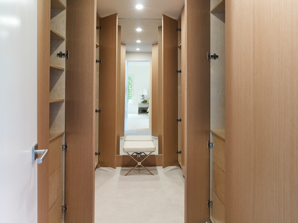 Modelo de armario vestidor unisex minimalista grande con armarios con paneles lisos, puertas de armario de madera clara, moqueta y suelo blanco