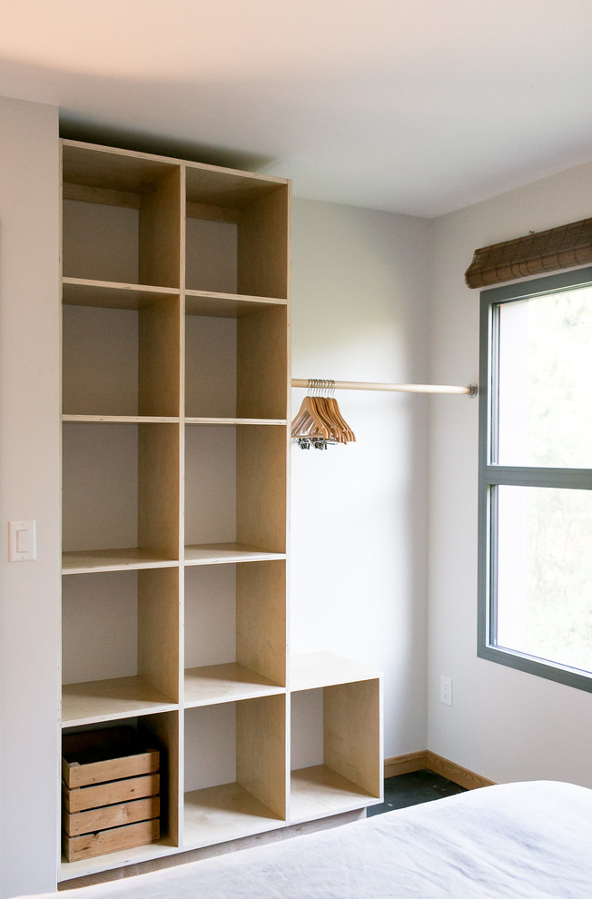 Réalisation d'un petit dressing room minimaliste en bois clair avec un placard sans porte, sol en béton ciré et un sol gris.