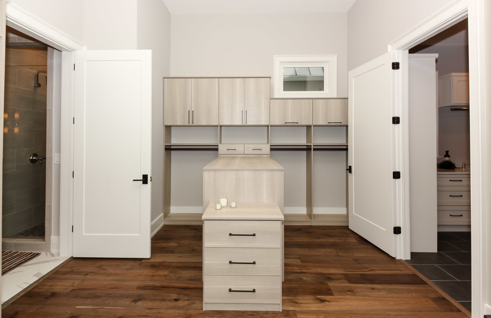 Imagen de armario vestidor unisex campestre de tamaño medio con armarios con paneles lisos, puertas de armario de madera clara y suelo de madera en tonos medios