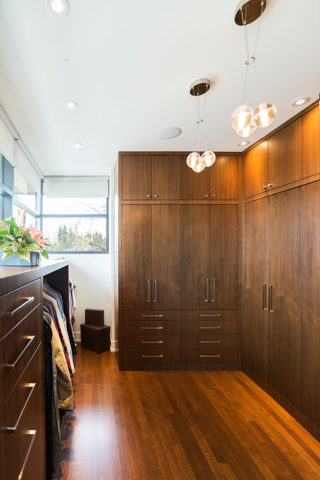 Cette photo montre un très grand dressing moderne en bois brun neutre avec un placard à porte plane et un sol en bois brun.