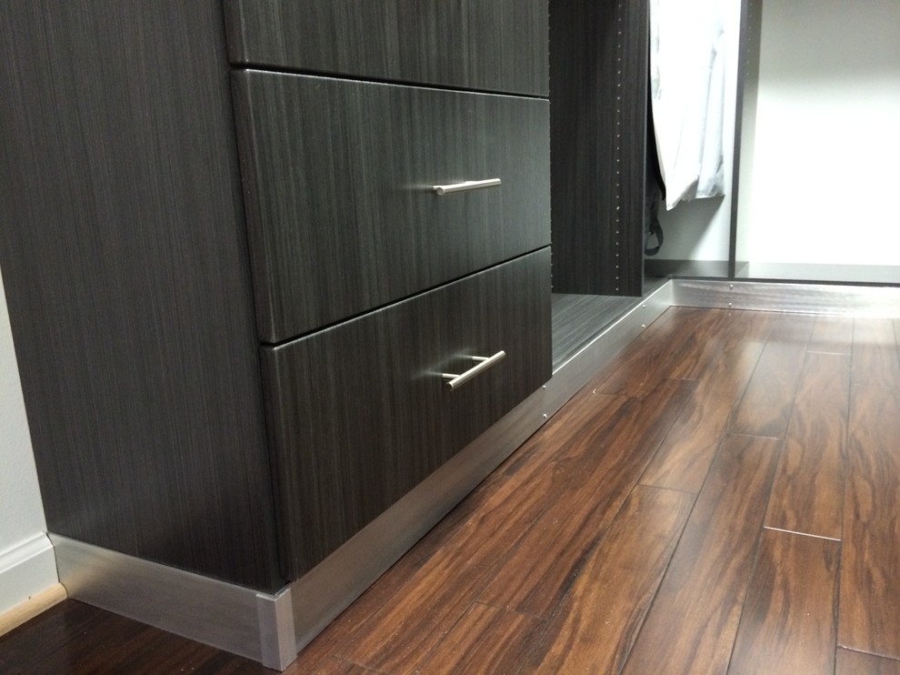 Bild på ett litet funkis walk-in-closet, med släta luckor, grå skåp, mörkt trägolv och brunt golv