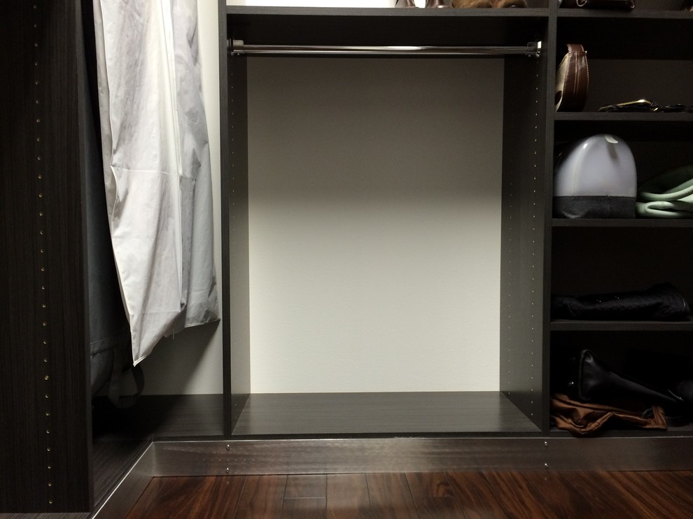 Bild på ett litet funkis walk-in-closet, med släta luckor, grå skåp, mörkt trägolv och brunt golv
