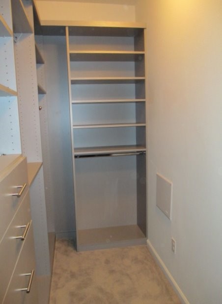 This is an example of a small modern gender neutral walk-in wardrobe in Los Angeles with flat-panel cabinets, grey cabinets, carpet and beige floors.