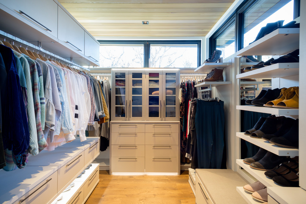 Diseño de vestidor de mujer minimalista grande con armarios con paneles lisos, puertas de armario de madera clara y suelo de madera en tonos medios