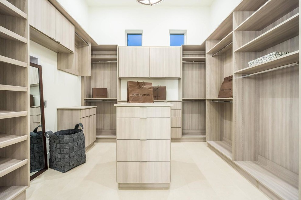Diseño de armario vestidor unisex minimalista extra grande con armarios con paneles lisos, puertas de armario de madera clara, suelo de baldosas de porcelana y suelo beige