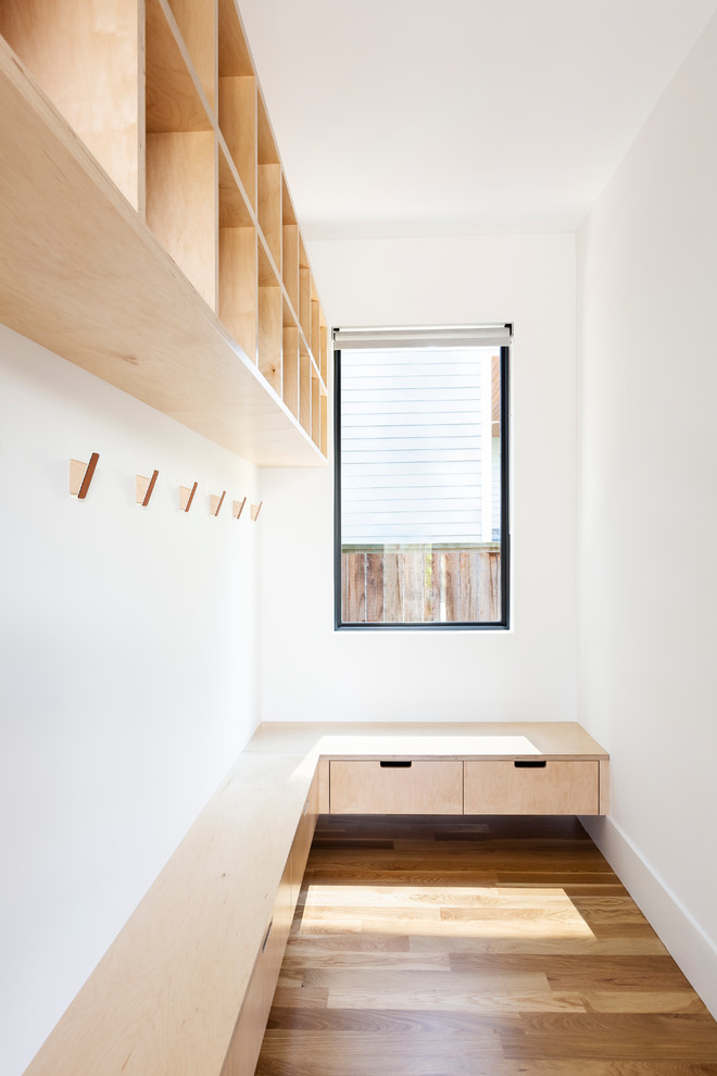 Réalisation d'un petit dressing minimaliste en bois clair neutre avec un placard à porte plane, parquet clair et un sol marron.