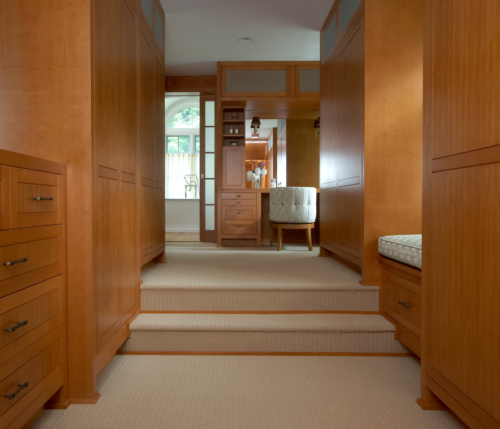 Modelo de vestidor unisex minimalista extra grande con armarios con paneles lisos, puertas de armario de madera clara, moqueta y suelo beige