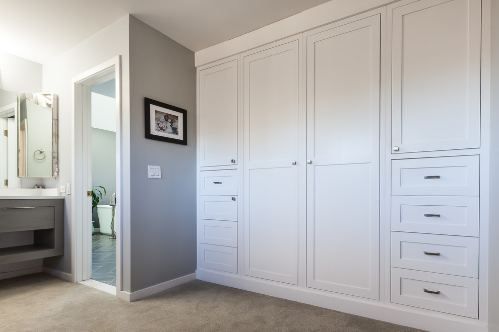 Ejemplo de armario de hombre moderno grande con armarios estilo shaker, puertas de armario blancas, moqueta y suelo beige