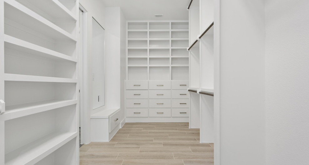 Diseño de armario vestidor unisex campestre grande con armarios estilo shaker, puertas de armario blancas, suelo de baldosas de cerámica y suelo beige