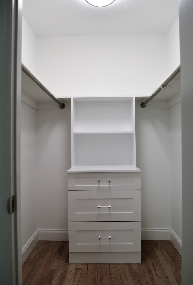 Photo of a small retro gender neutral walk-in wardrobe in New York with shaker cabinets, white cabinets and light hardwood flooring.