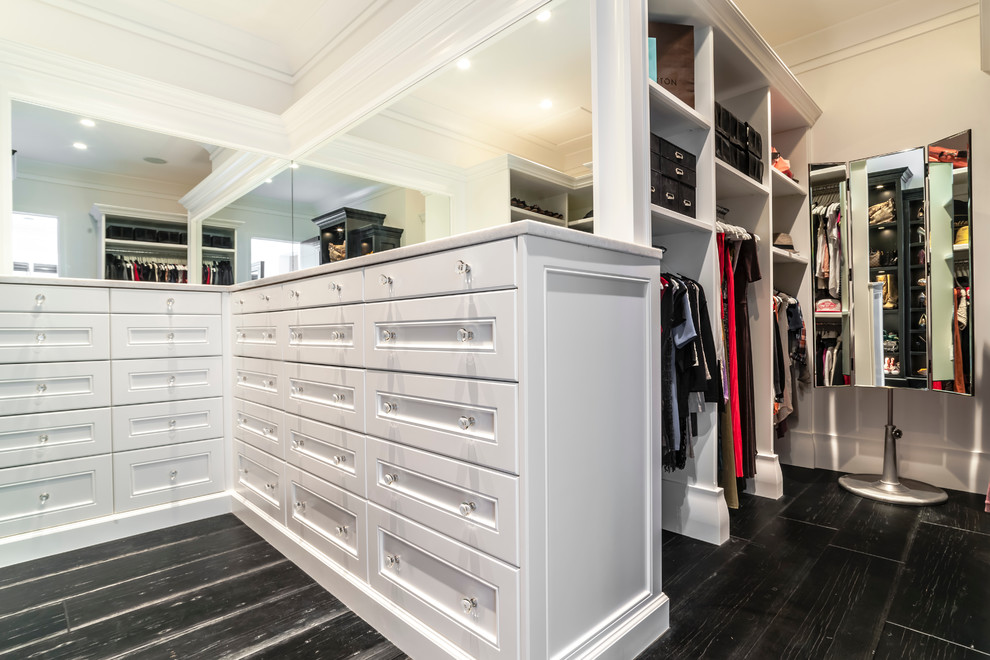 Diseño de armario vestidor de mujer minimalista extra grande con armarios abiertos, suelo de madera oscura y puertas de armario blancas