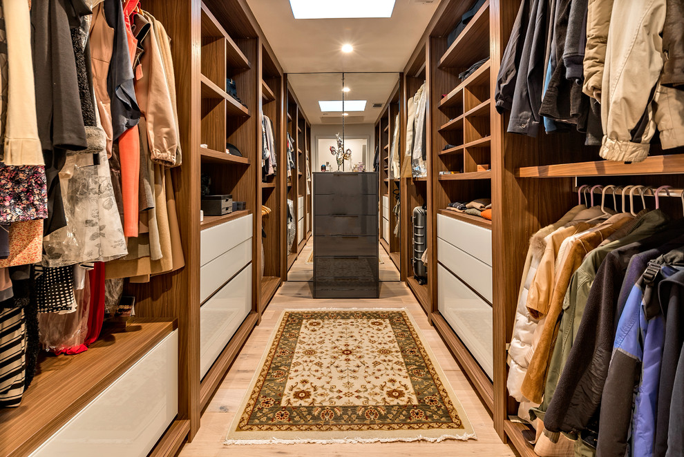 Modelo de armario vestidor unisex contemporáneo con armarios abiertos, puertas de armario de madera oscura, suelo de madera clara y suelo beige