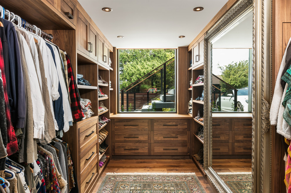 Modelo de armario vestidor unisex rústico de tamaño medio con armarios estilo shaker, puertas de armario de madera oscura, suelo de madera en tonos medios y suelo marrón