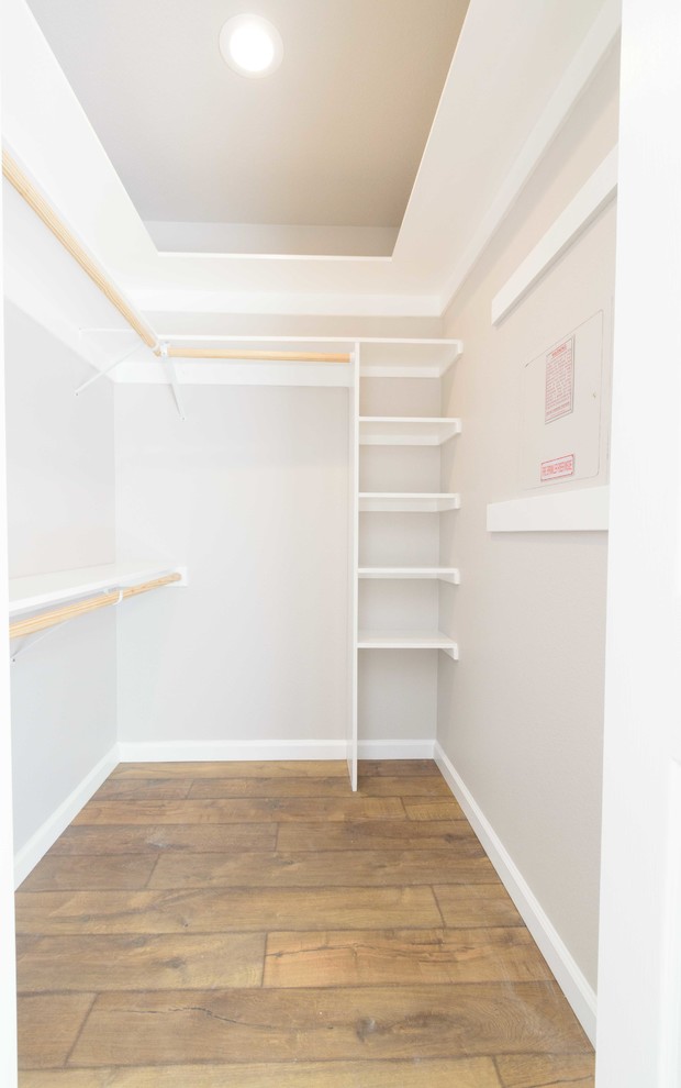 Imagen de armario vestidor unisex clásico renovado de tamaño medio con puertas de armario blancas, suelo laminado y suelo marrón