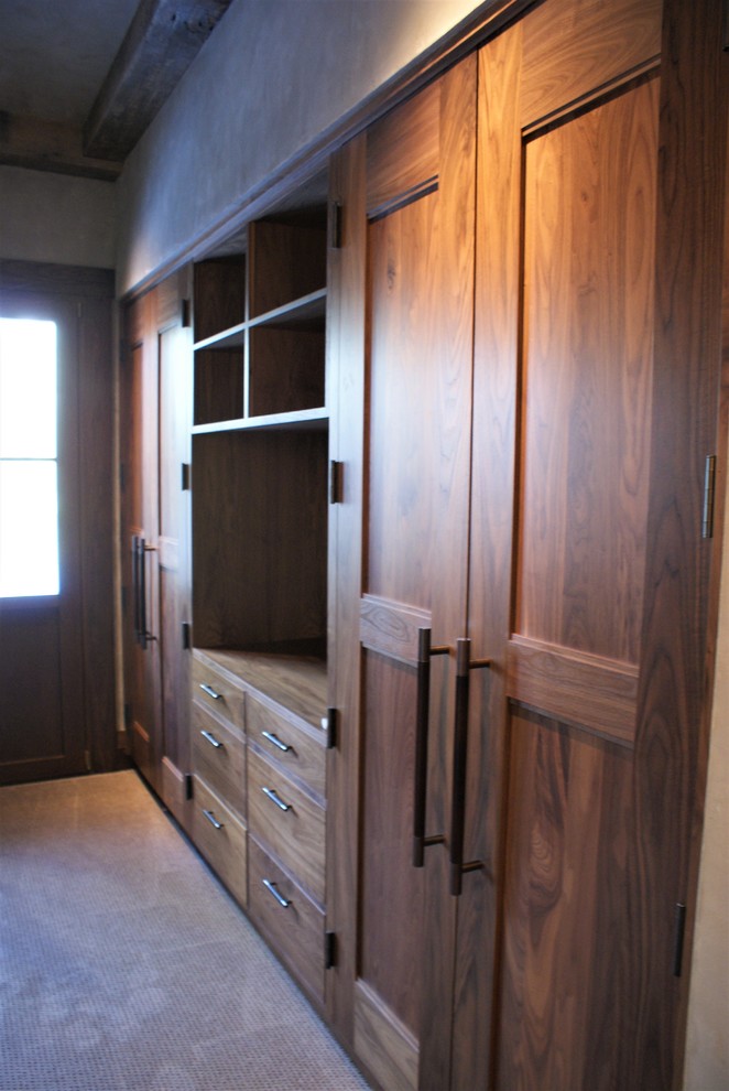 Imagen de vestidor unisex clásico grande con armarios con paneles empotrados, puertas de armario de madera oscura y moqueta