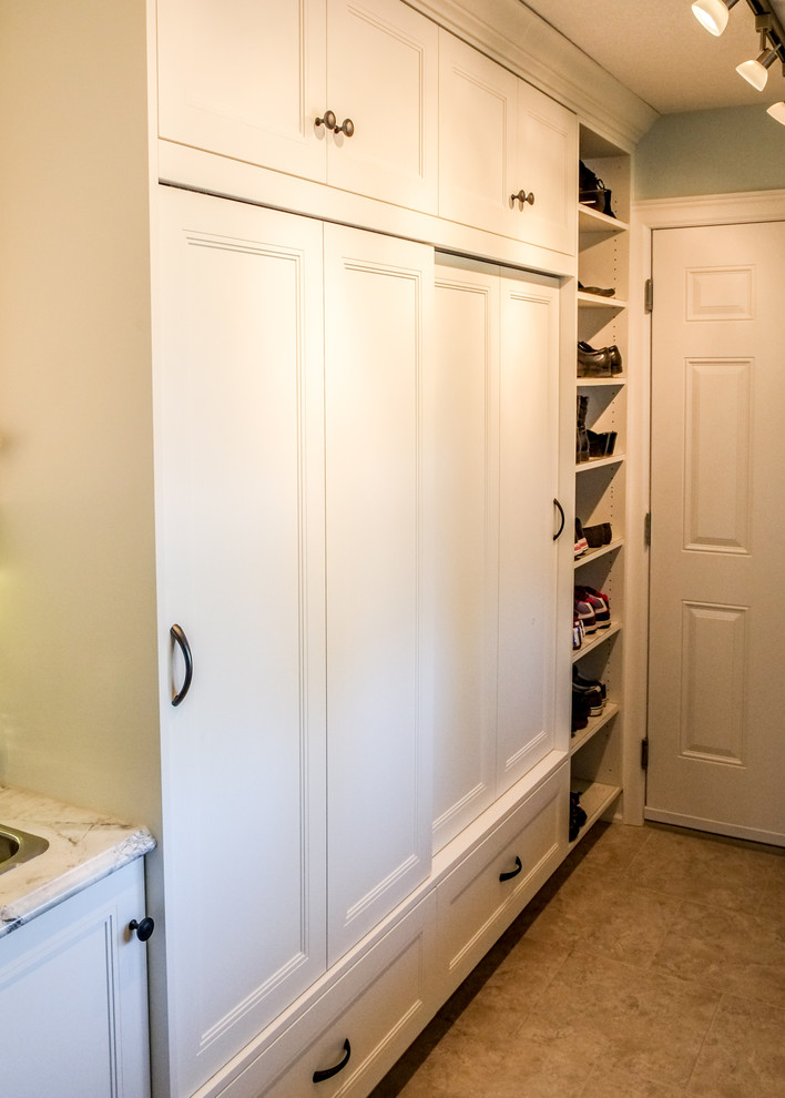 Aménagement d'un placard dressing classique de taille moyenne et neutre avec un placard avec porte à panneau encastré, des portes de placard blanches et un sol en linoléum.