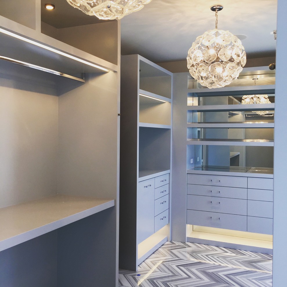 Large contemporary dressing room for women in Los Angeles with flat-panel cabinets, grey cabinets and marble flooring.