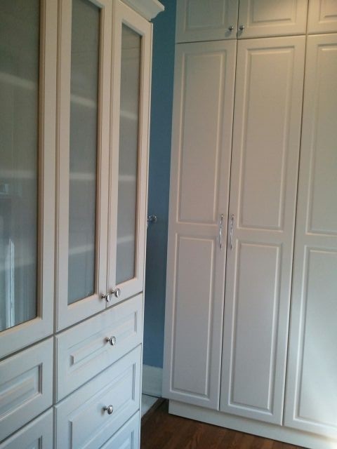 Imagen de armario vestidor unisex actual pequeño con armarios tipo vitrina, puertas de armario blancas y suelo de madera oscura