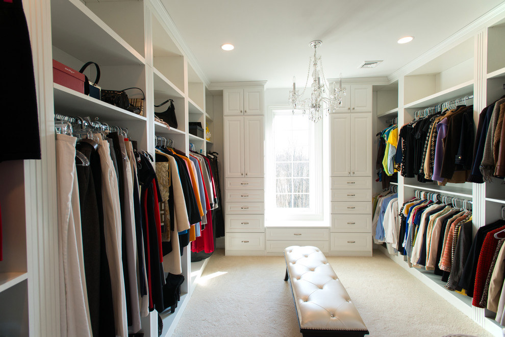 Ejemplo de armario vestidor unisex tradicional grande con armarios con paneles con relieve, puertas de armario blancas, moqueta y suelo beige