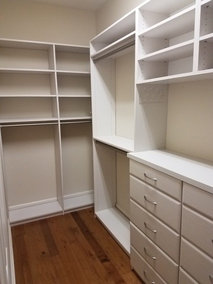 Inspiration for a small classic gender neutral walk-in wardrobe in Miami with flat-panel cabinets, white cabinets and medium hardwood flooring.