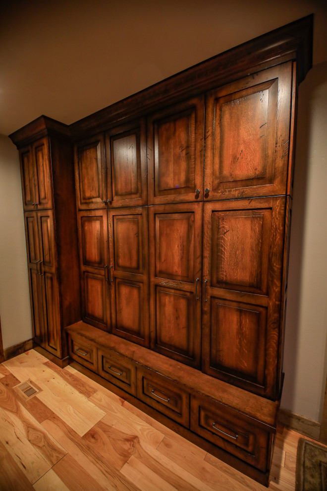 Diseño de armario rústico de tamaño medio con armarios con paneles con relieve, puertas de armario de madera en tonos medios, suelo de madera en tonos medios y suelo marrón