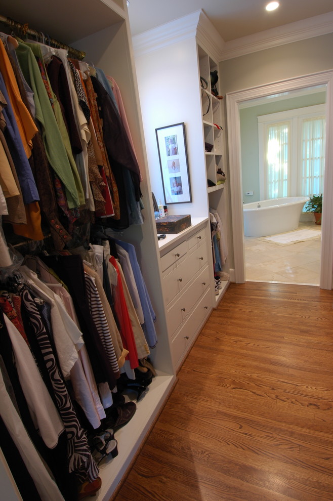 Inspiration pour un grand dressing room traditionnel neutre avec un placard à porte plane, des portes de placard blanches et un sol en bois brun.