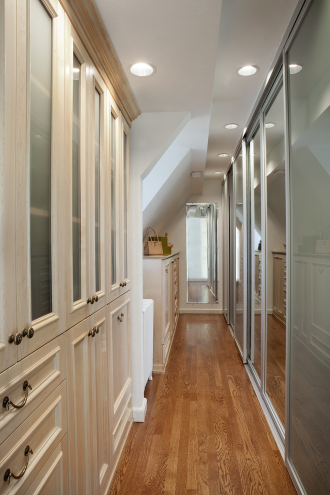 Photo of a large classic gender neutral dressing room in New York with recessed-panel cabinets, light wood cabinets and medium hardwood flooring.