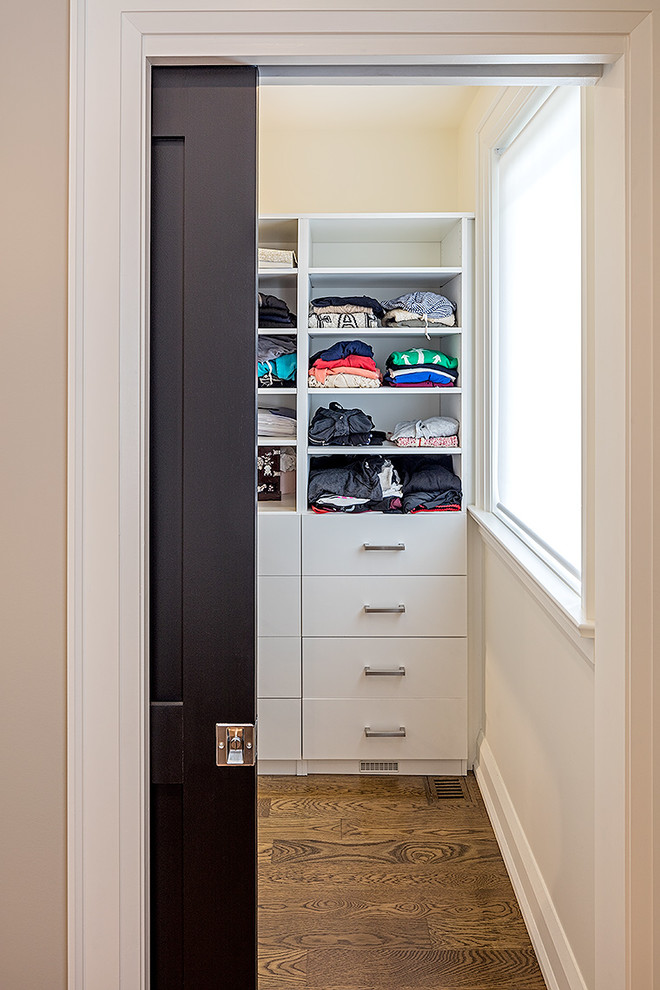 Imagen de armario vestidor unisex tradicional renovado de tamaño medio con armarios con paneles lisos, puertas de armario blancas y suelo de madera en tonos medios