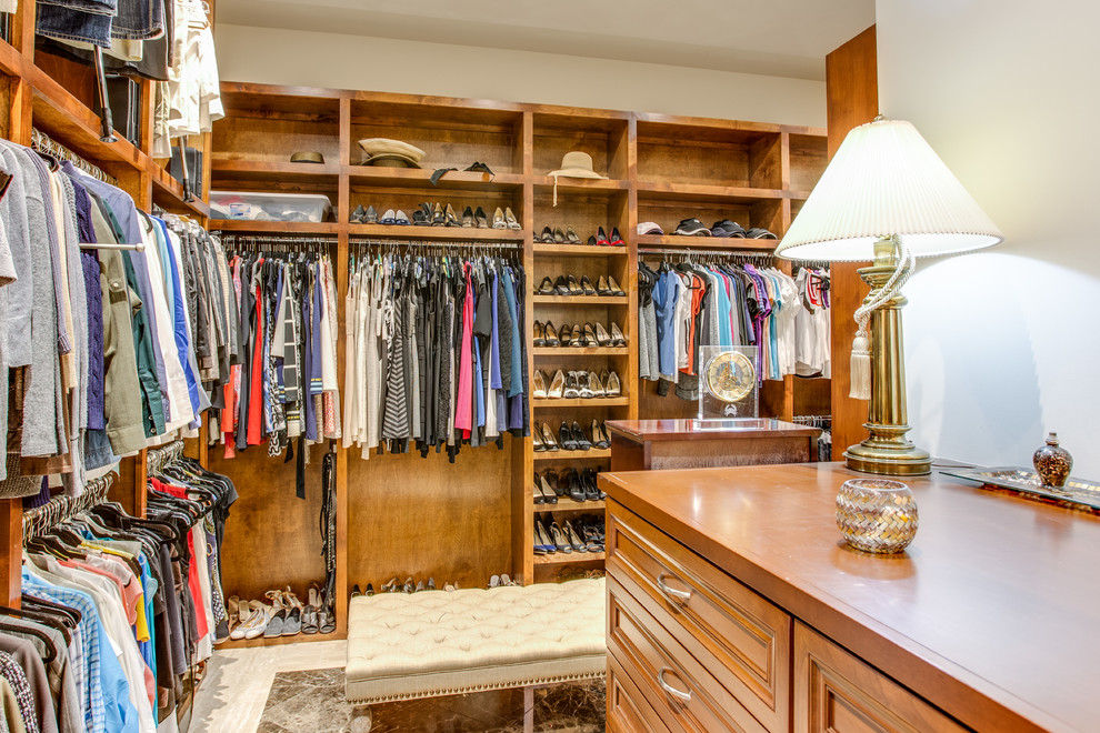 Photo of a large classic dressing room for women in Austin with raised-panel cabinets, medium wood cabinets, marble flooring and white floors.