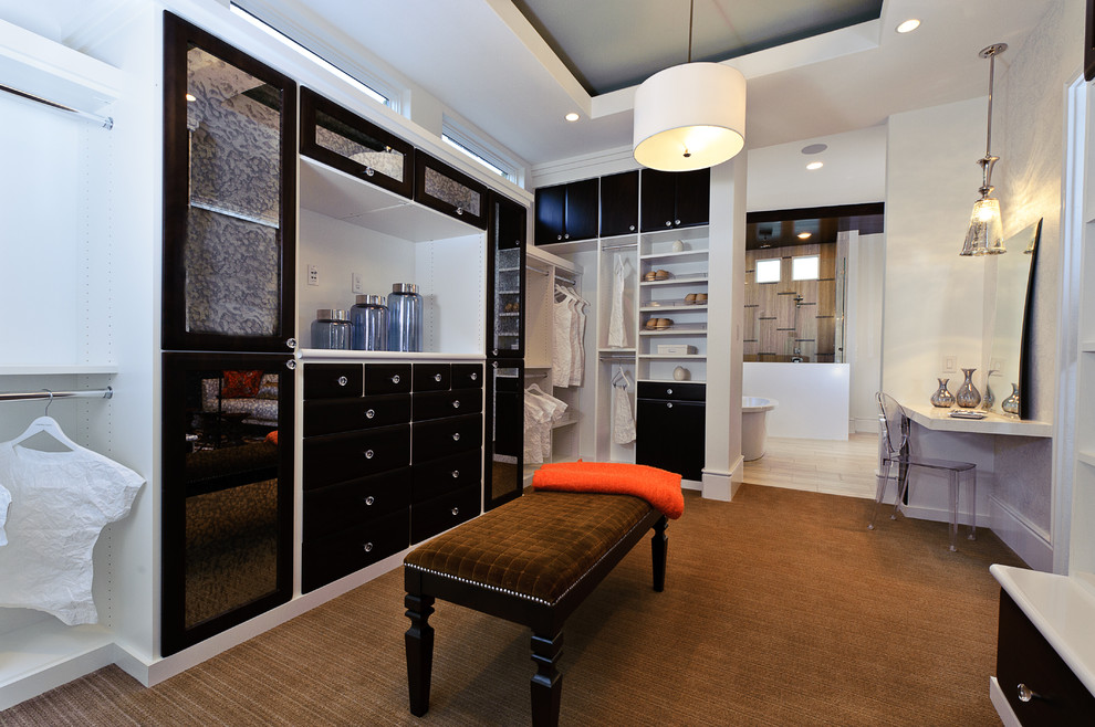 Пример оригинального дизайна: большая гардеробная комната унисекс в стиле неоклассика (современная классика) с черными фасадами, ковровым покрытием, плоскими фасадами и коричневым полом