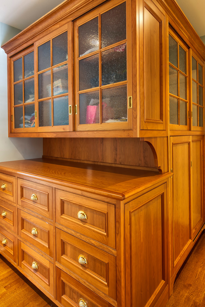 Foto di una cabina armadio unisex chic con ante a filo, ante in legno scuro e pavimento in legno massello medio