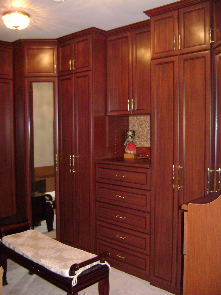 Modelo de armario vestidor unisex clásico de tamaño medio con armarios con paneles empotrados, puertas de armario de madera oscura y moqueta